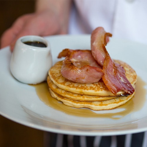 Bacon and syrup pancakes being served